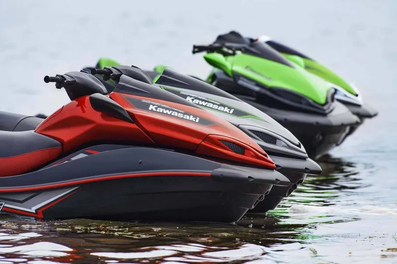 Slide: The Image of Three Kawasaki Jet Skis in red, black, and green at the edge of a body of water. - 12