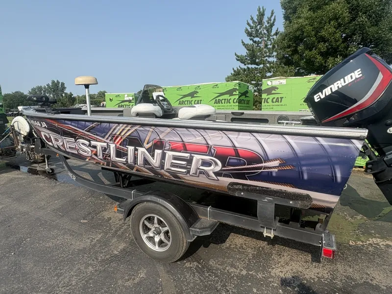 The Image of A 2014 Crestliner 1850 Fish Hawk boat on a trailer, featuring an Evinrude motor. - 1