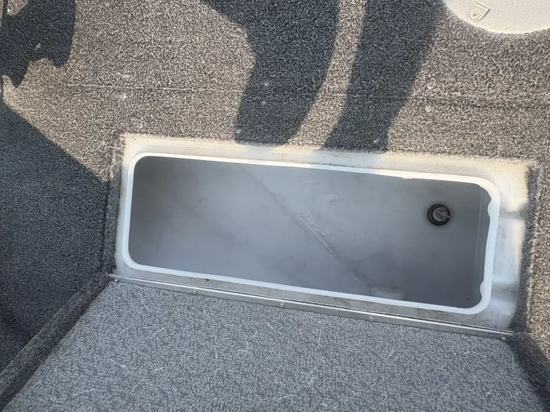 Slide: The Image of An open storage compartment on a boat with gray carpeted flooring. - 11
