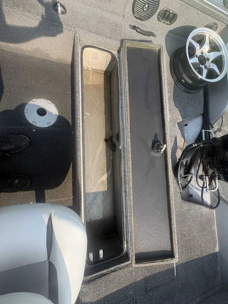 Slide: The Image of The image shows the interior of a 2014 Crestliner 1850 Fish Hawk boat with an open storage compartment. - 18