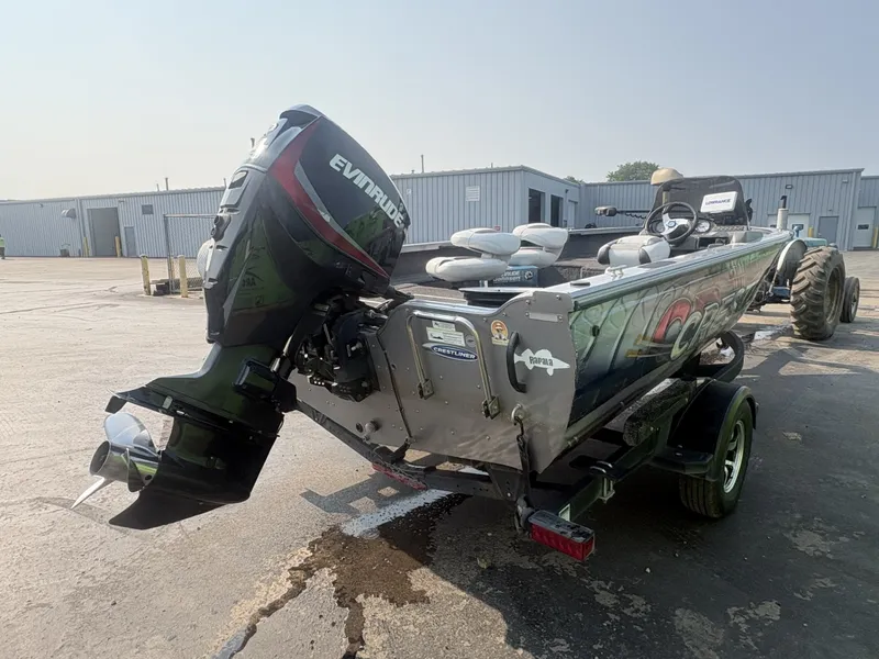 Slide: The Image of A 2014 Crestliner 1850 Fish Hawk with an Evinrude outboard motor, on a trailer in an industrial area. - 3