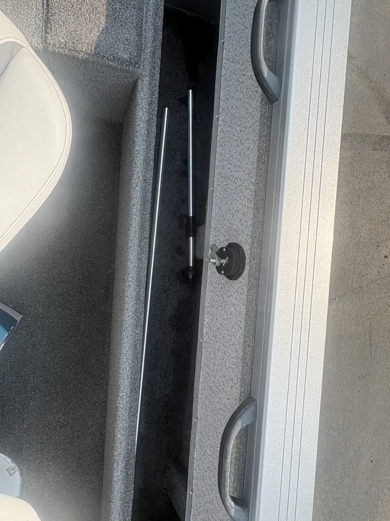 Slide: The Image of A storage compartment in a boat with gray carpeting and two metal rods. - 17