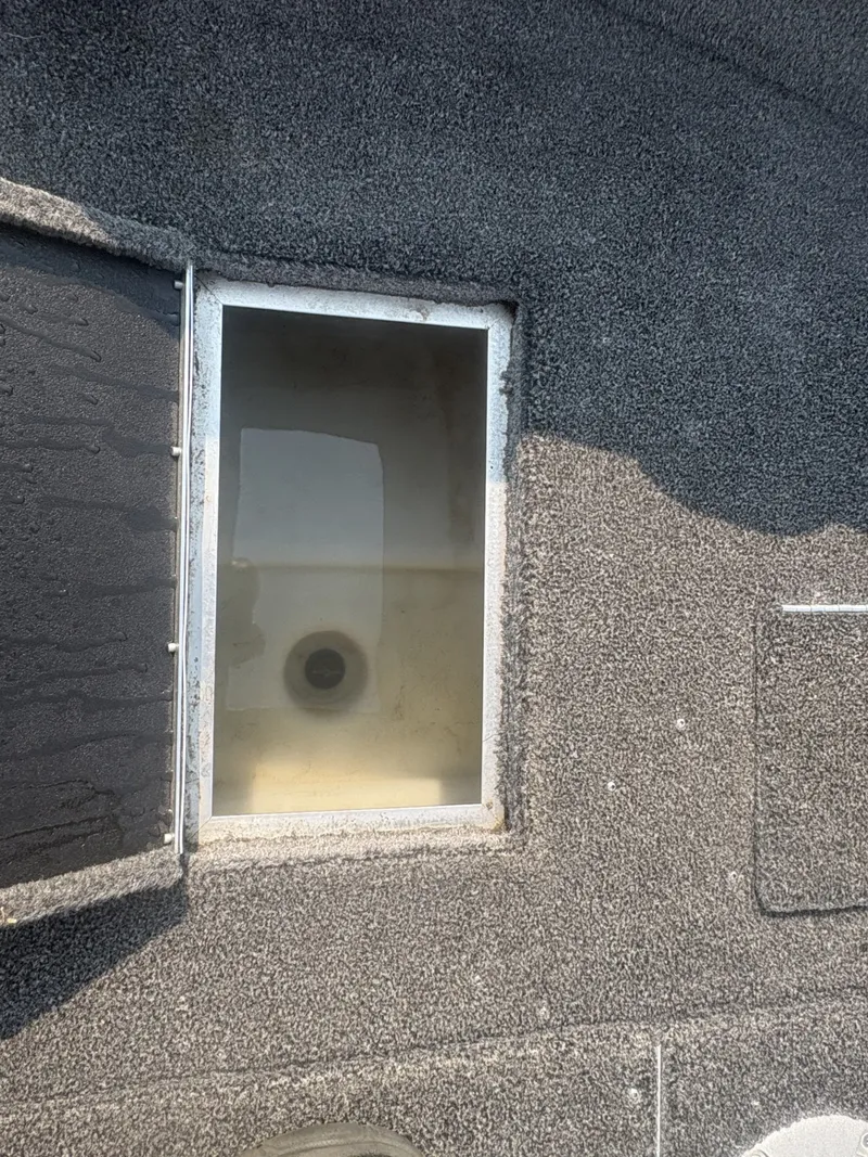 Slide: The Image of An open storage compartment on a boat with gray carpeted flooring. - 16