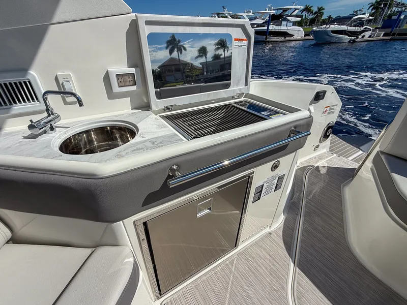 Slide: The Image of The 2027 Sea Ray Sundancer 320 Outboard features a sleek outdoor kitchen with a sink and grill. - 17