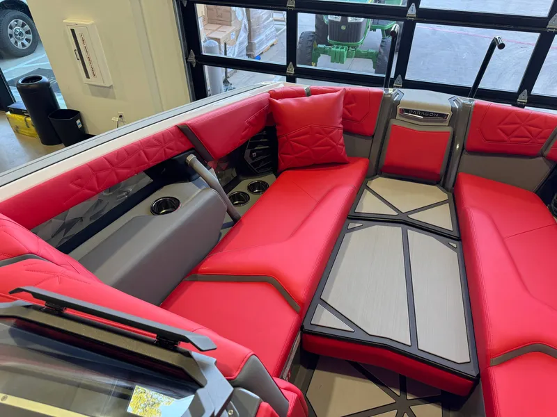 Slide: The Image of The image shows the interior of a 2027 Nautique Super Air Nautique G25 Paragon. The seating is bright red with gray accents. A table is positioned in the center of the seating area. - 21