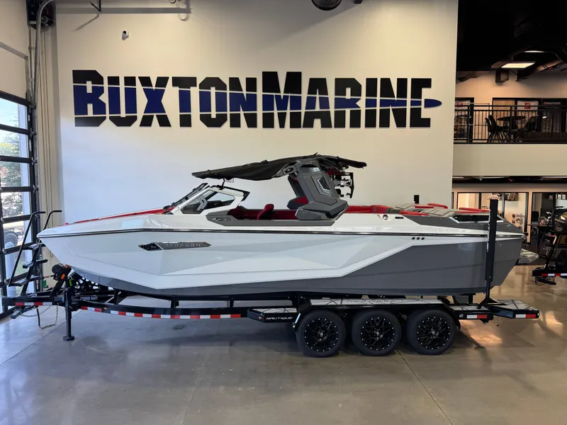 The Image of A sleek, modern boat with a gray hull and red interior sits on a trailer in a showroom. - 1