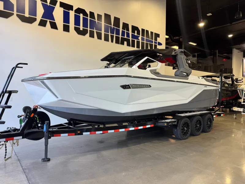 Slide: The Image of A modern, white Nautique Super Air Nautique G25 Paragon from 2027 on a trailer in a showroom. - 2