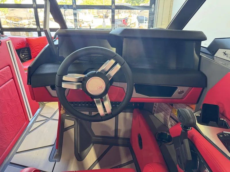 Slide: The Image of The cockpit of the 2027 Nautique Super Air Nautique G25 Paragon features a modern steering wheel and red upholstery. - 28