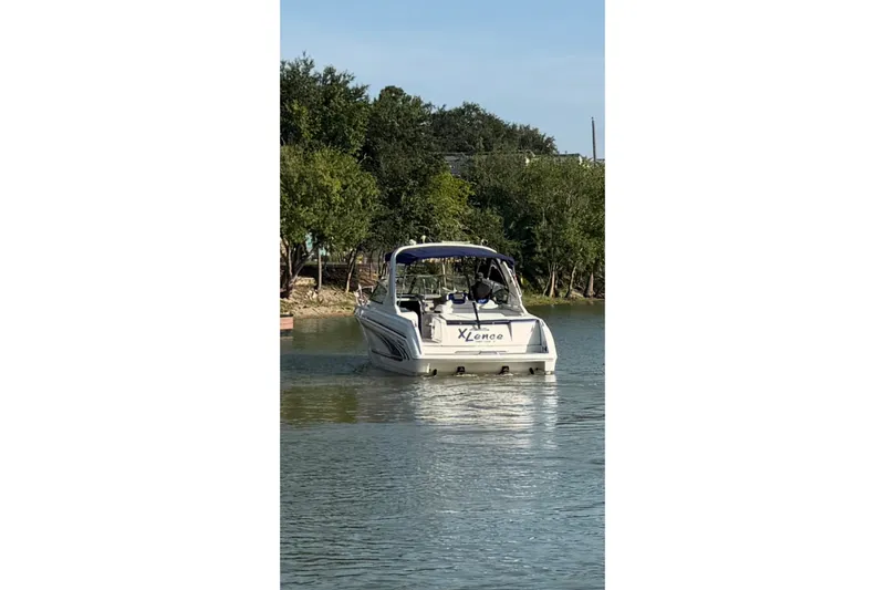 Slide: The Image of 2003 Formula 330 Sun Sport boat on a calm lake, surrounded by trees. - 2