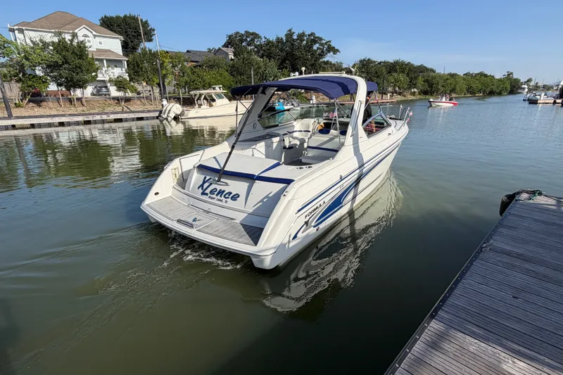 Slide: The Image of 2003 Formula 330 Sun Sport boat cruising on a calm waterway near a dock. - 4