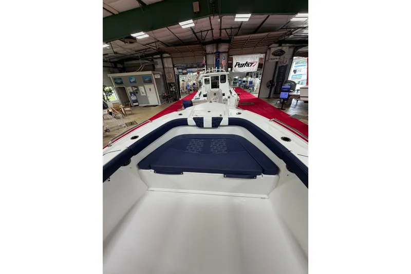 Slide: The Image of 2027 Parker 240 Coastal Elite boat interior with blue seating, displayed in a showroom. - 17
