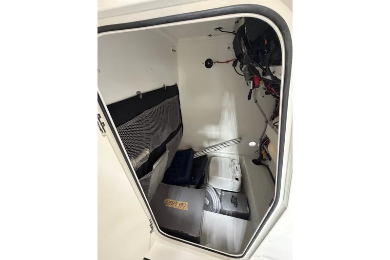 Slide: The Image of Interior storage compartment of 2027 Parker 240 Coastal Elite boat, featuring organized equipment and wiring. - 20