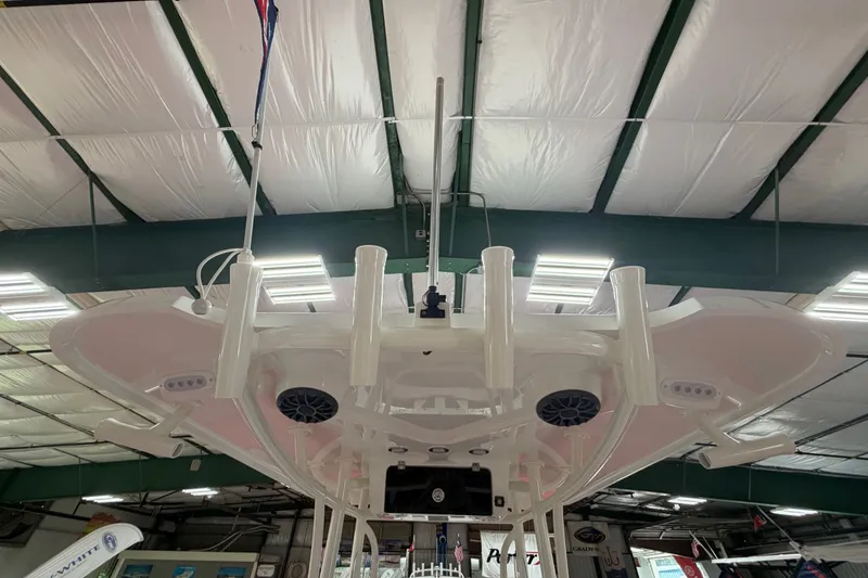 Slide: The Image of 2027 Parker 240 Coastal Elite boat interior, showcasing ceiling speakers and rod holders in a showroom. - 13