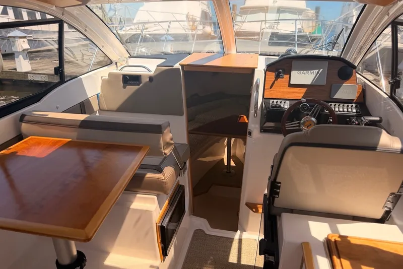 Slide: The Image of Interior of 2022 Cutwater C-24 Coupe boat with helm, seating, and wooden table. - 6