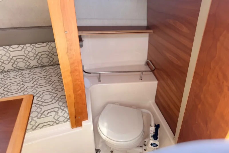 Slide: The Image of 2022 Cutwater C-24 Coupe interior bathroom with wooden accents and patterned upholstery. - 13
