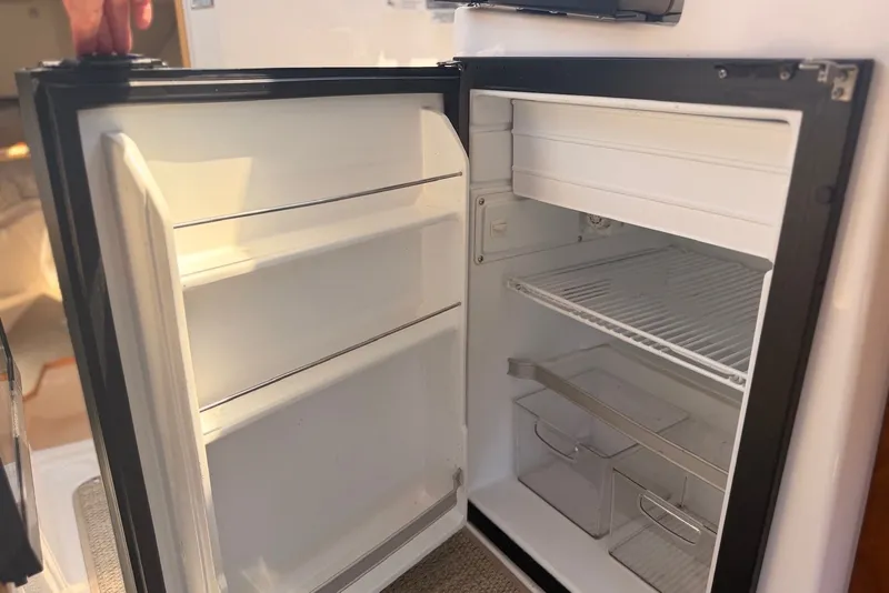 Slide: The Image of Open refrigerator inside 2022 Cutwater C-24 Coupe boat, showcasing shelves and storage compartments. - 12
