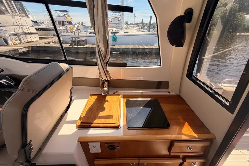 Slide: The Image of Interior of 2022 Cutwater C-24 Coupe with wooden countertop and marina view. - 8