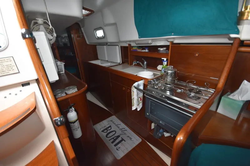 Slide: The Image of Interior of 1999 Beneteau Oceanis 36 CC sailboat, featuring a compact kitchen with stove and sink. - 31