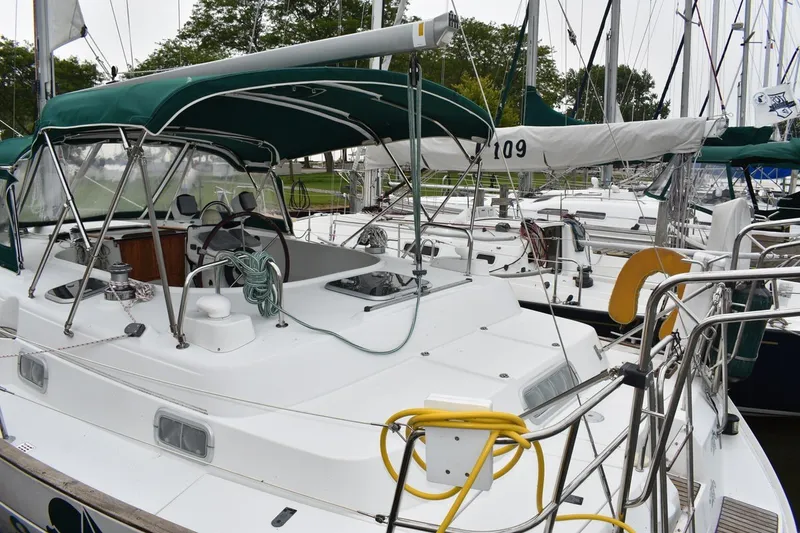 Slide: The Image of 1999 Beneteau Oceanis 36 CC sailboat docked, featuring green canopy and well-equipped cockpit. - 8