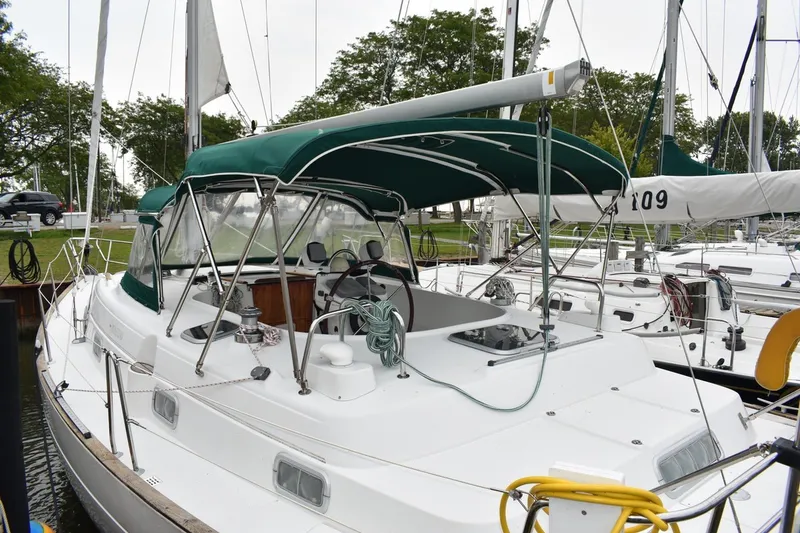 Slide: The Image of 1999 Beneteau Oceanis 36 CC sailboat docked, featuring green canopy and sleek design. - 9