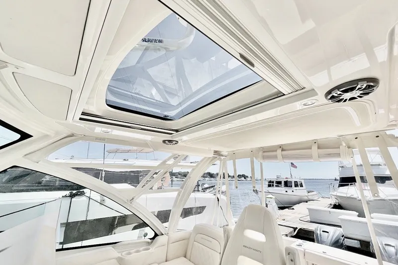 Slide: The Image of Interior view of 2023 Grady-White Express 330 boat with open sunroof and docked yachts. - 25