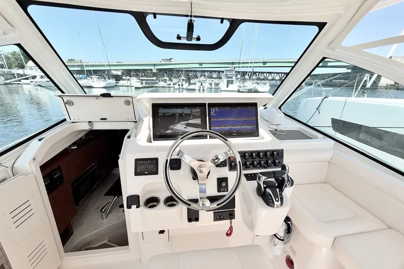 Slide: The Image of 2023 Grady-White Express 330 helm with modern controls and navigation screens at marina. - 19
