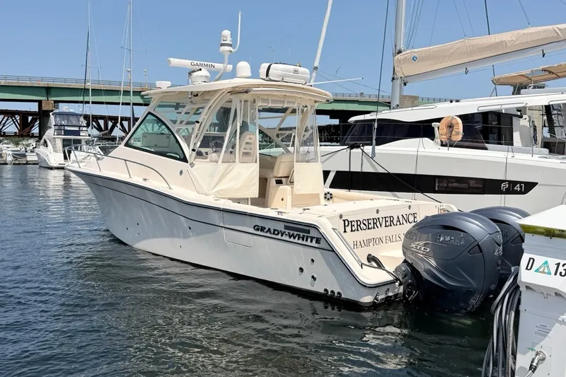 Slide: The Image of 2023 Grady-White Express 330 boat docked in marina, featuring twin Yamaha engines. - 2