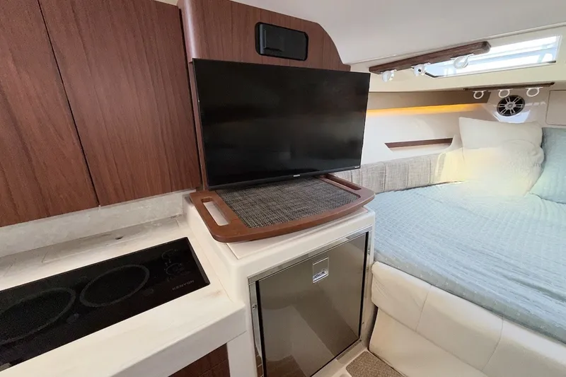 Slide: The Image of 2023 Grady-White Express 330 cabin interior with TV, kitchenette, and bed. - 3