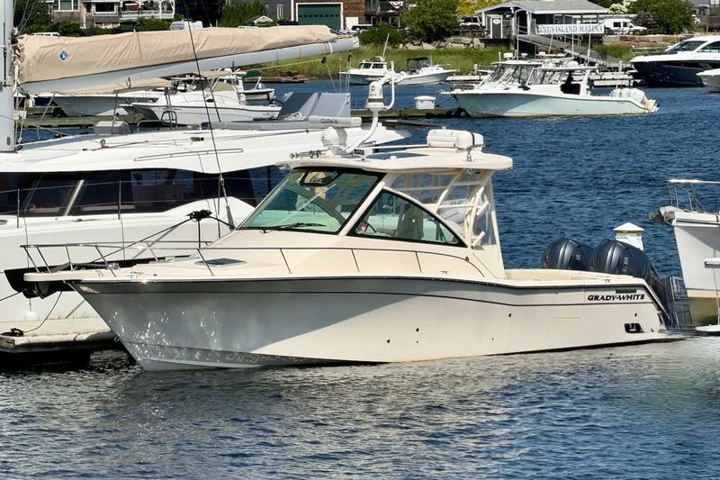 Slide: The Image of 2023 Grady-White Express 330 boat docked in a marina, surrounded by other vessels. - 49