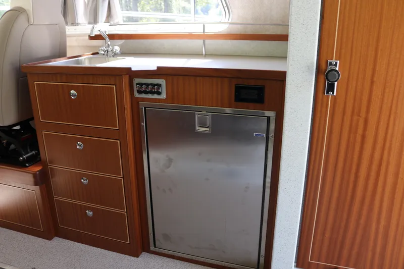 Slide: The Image of 2026 KingFisher 3425 GFX Offshore boat interior with wooden cabinetry and stainless steel fridge. - 13