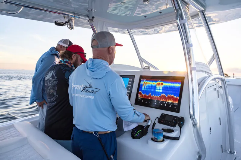Slide: The Image of Three people on a 2025 Front Runner 36 Center Console boat, using navigation equipment. - 7