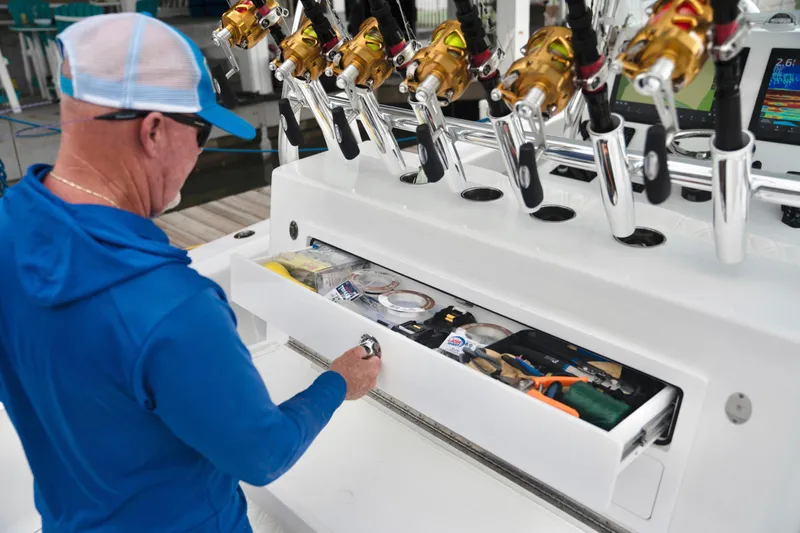 Slide: The Image of Man accessing storage on 2025 Front Runner 36 Center Console boat with fishing rods. - 13