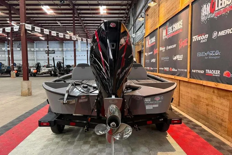 Slide: The Image of 2026 Tracker Savage 215 boat displayed in a showroom with promotional banners. - 3