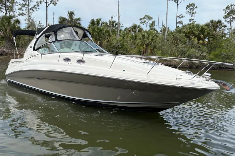 The Image of 2007 Sea Ray Sundancer 320 boat cruising on a calm river with lush greenery. - 0