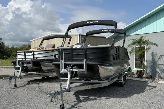 Slide: The Image of Two 2027 Evotti 523CS pontoon boats on trailers, parked outdoors near a building. - 3