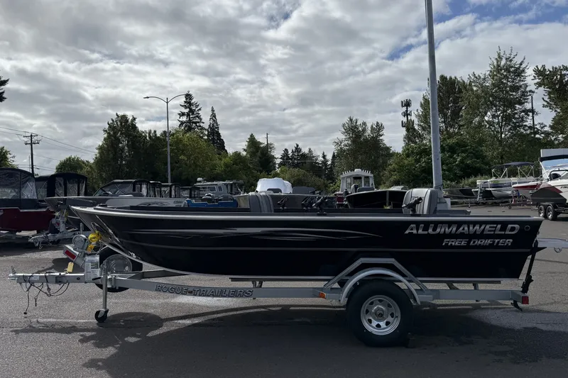 Slide: The Image of 2027 Alumaweld Free Drifter 18 boat on trailer, parked outdoors under cloudy sky. - 4