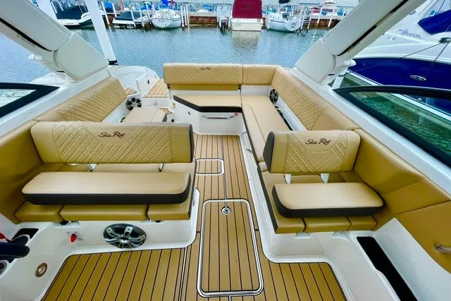 Slide: The Image of Luxurious 2025 Sea Ray SDX 270 boat interior with tan seating and teak flooring at a marina. - 1