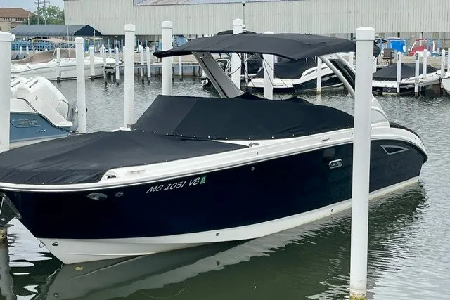 The Image of 2025 Sea Ray SDX 270 boat docked, covered with black canvas, in a marina setting. - 0