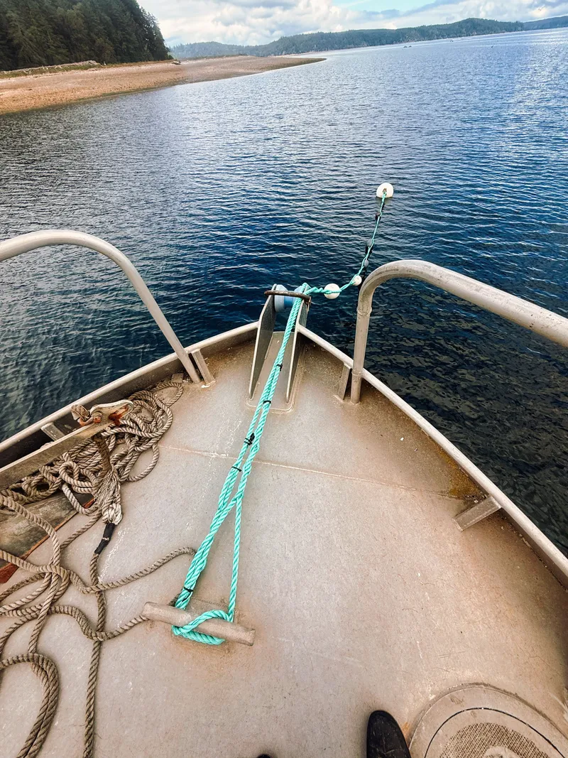 Slide: The Image of Bow of a boat with ropes and anchor, surrounded by calm water and wooded shoreline. - 3