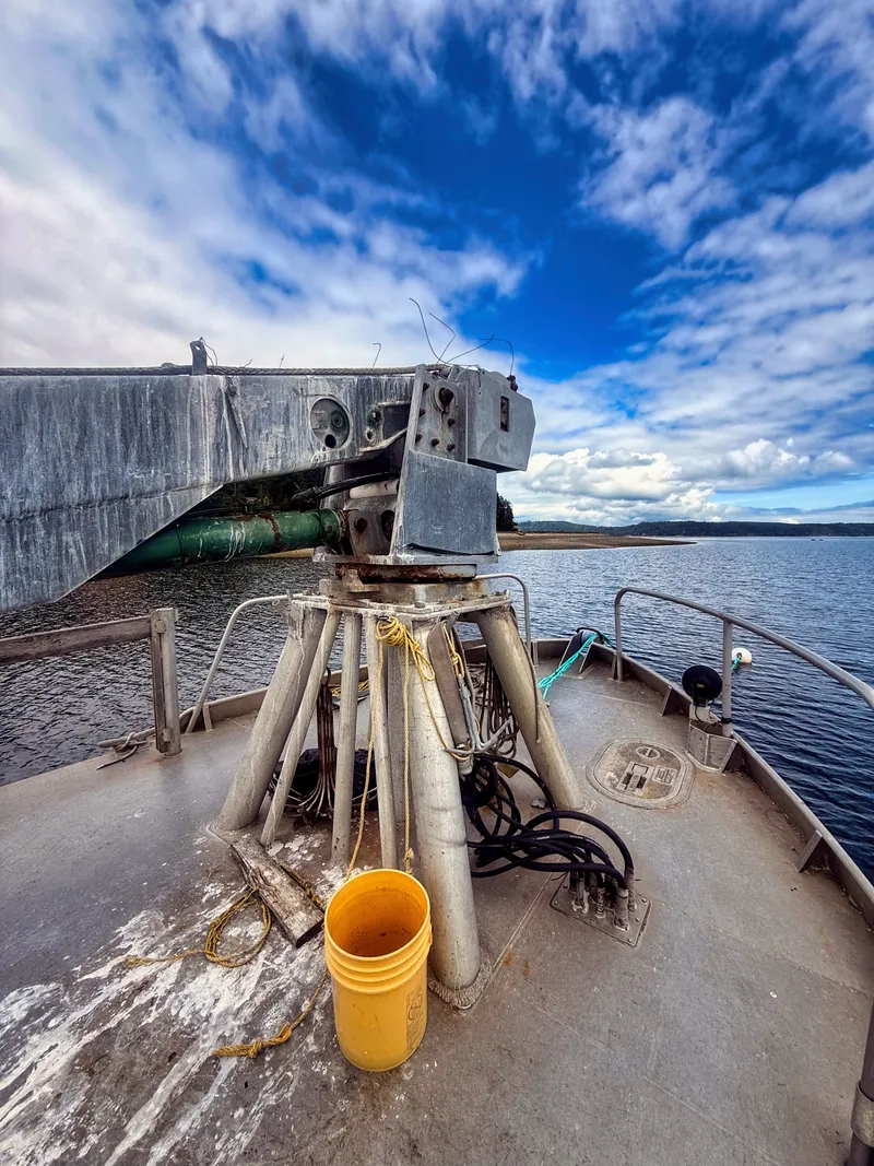 Slide: The Image of The deck of an aluminum oyster boat with a sturdy crane and a yellow bucket. - 2