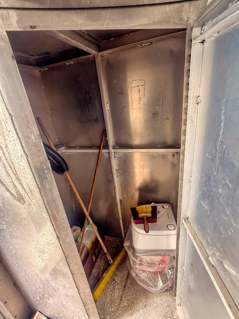 Slide: The Image of A small space with aluminum walls, a bucket, broom, and cleaning supplies. - 15