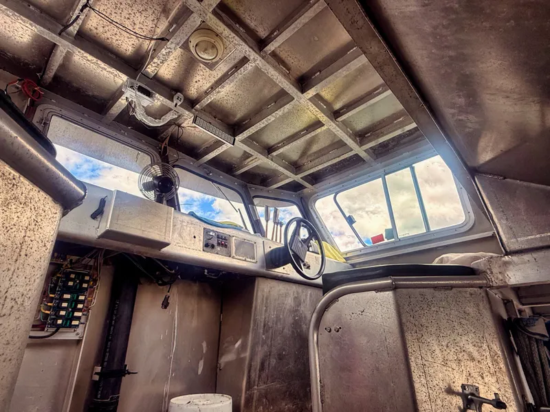 Slide: The Image of Interior view of a rugged aluminum boat with a helm and windows showing the sky. - 16