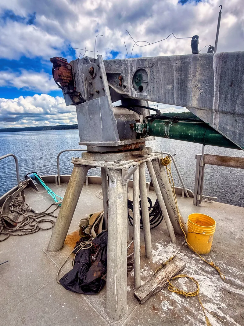 Slide: The Image of A sturdy crane on a boat, surrounded by ropes and a yellow bucket, overlooking the water. - 20