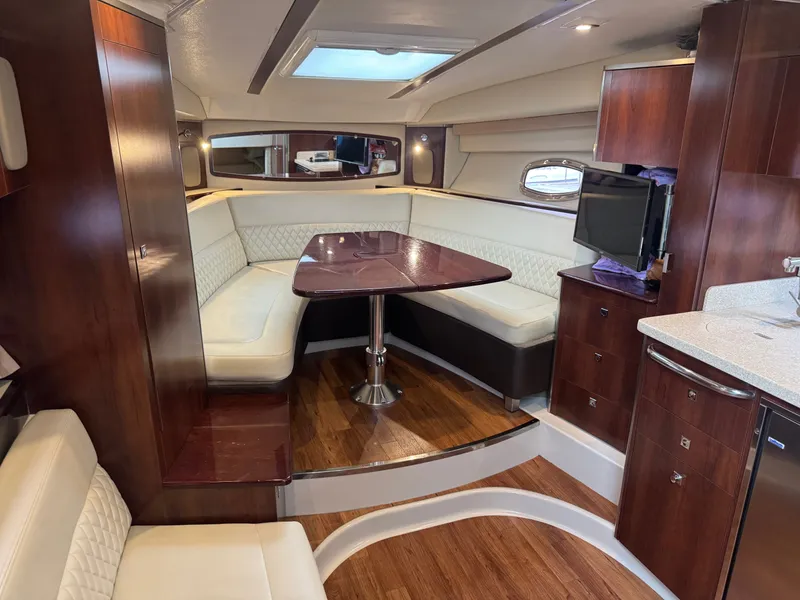 Slide: The Image of The interior of a 2018 Chaparral 330 Signature features an elegant seating area with a wooden table. - 12