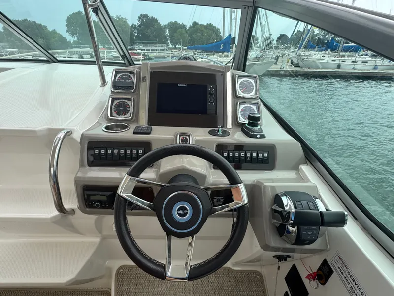 Slide: The Image of The cockpit of a 2018 Chaparral 330 Signature with modern steering, instruments, and a view of the marina. - 9