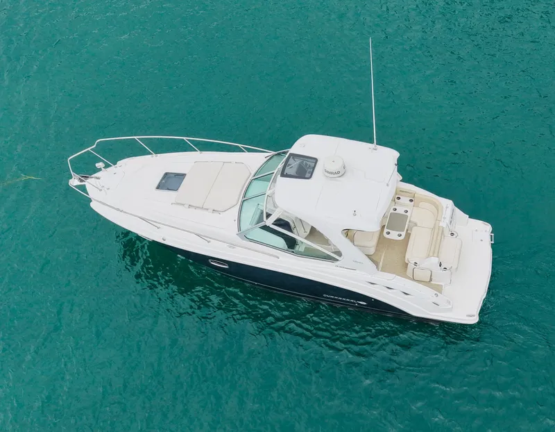 Slide: The Image of A 2018 Chaparral 330 Signature on clear turquoise water. It features a spacious deck and enclosed cabin. - 18
