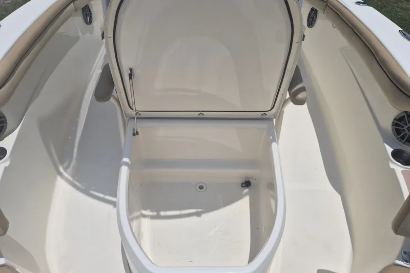 Slide: The Image of 2017 Scout 215 XSF boat storage compartment, open and empty, with beige seating and speakers. - 25