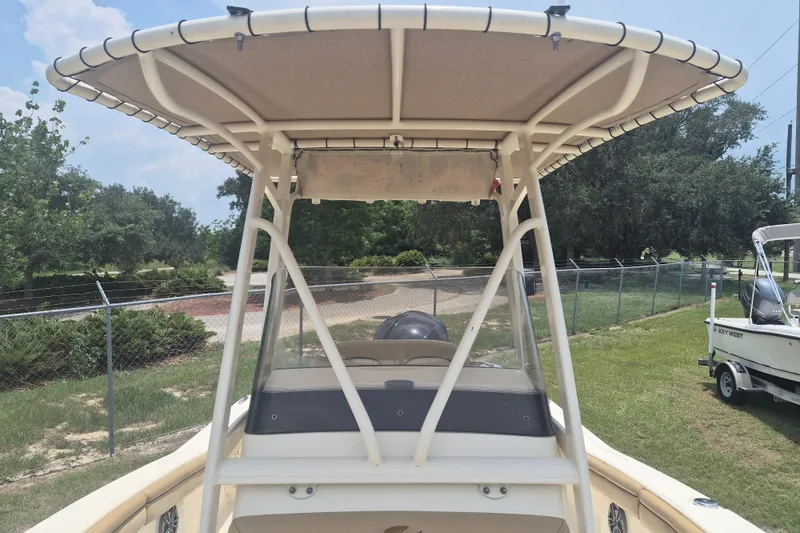 Slide: The Image of 2017 Scout 215 XSF boat with T-top, parked on grass near a fence. - 24
