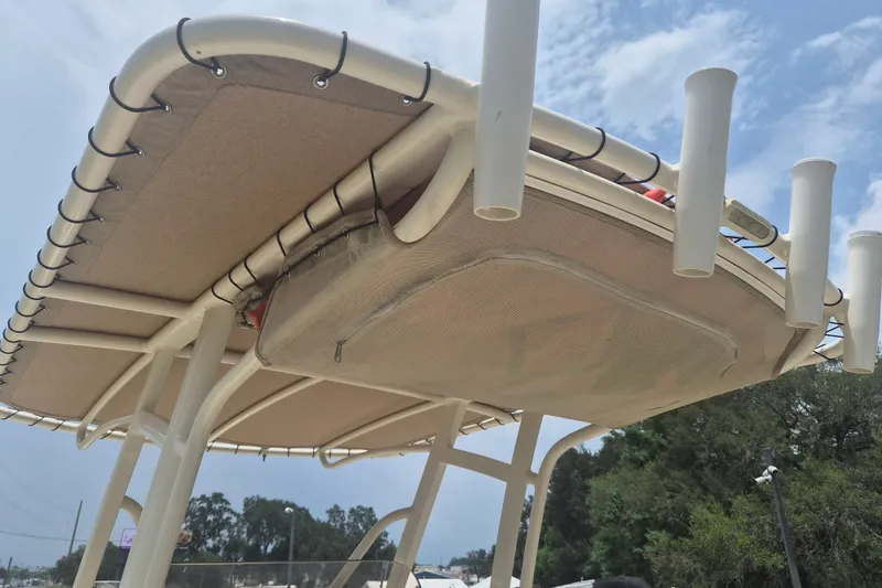 Slide: The Image of 2017 Scout 215 XSF boat T-top with rod holders and storage pouch under a clear sky. - 13