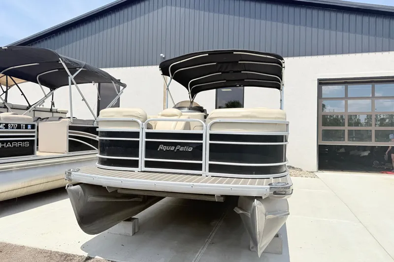 Slide: The Image of 2013 AquaPatio 240 RS pontoon boat parked outside a building. - 2